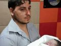 مواطن يحمل طفلته الميتة بين ذراعيه في مقر إذاعة محلية بغزة